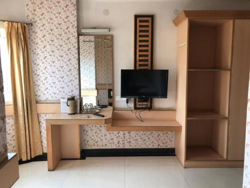a room with a desk with a television on it at Bharati Lodge in Hubli