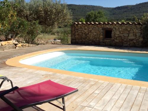 una piscina con una silla y un edificio en l'Oustaou B&B Piscine & Spa, en Besse-sur-Issole