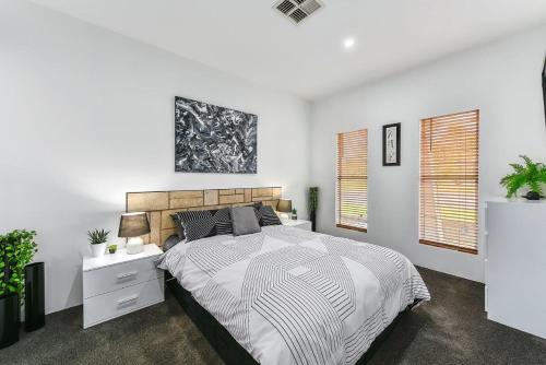 a white bedroom with a large bed and two windows at KENNEDY EXECUTIVE TOWNHOUSE in Mount Gambier