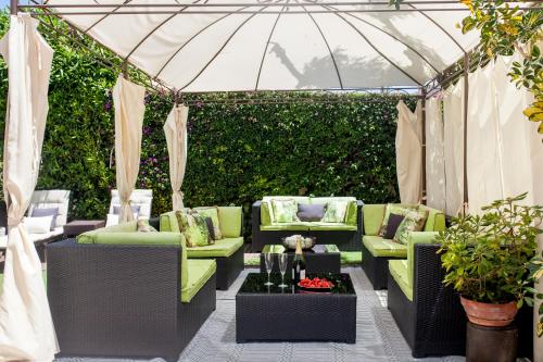 a patio with green furniture and an umbrella at New Opening Villa Oasis Terramar in Sitges