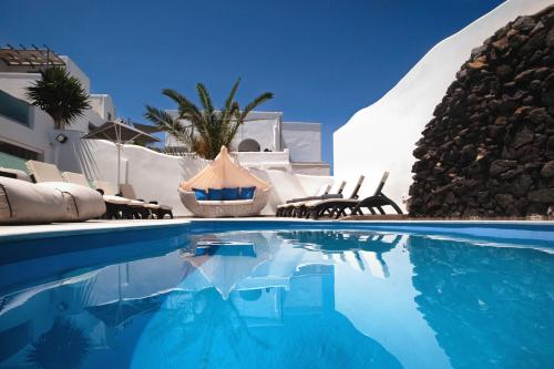 a swimming pool with chairs and a house at Irene City Villas in Fira