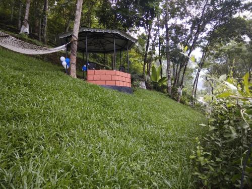 a hammock on a grassy hill with a gazebo at Mistywindvalley in Kudayattūr