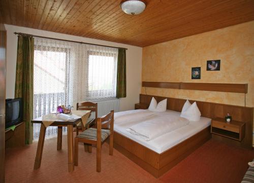 a bedroom with a bed and a table and a television at Marias Pension in Falkenstein