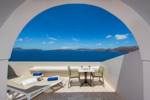 a balcony with a table and chairs and the ocean at Kokkinos Villas in Akrotiri
