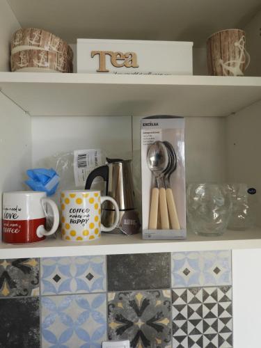 a shelf with cups and utensils in a kitchen at Red Rose Apartment in Portorož