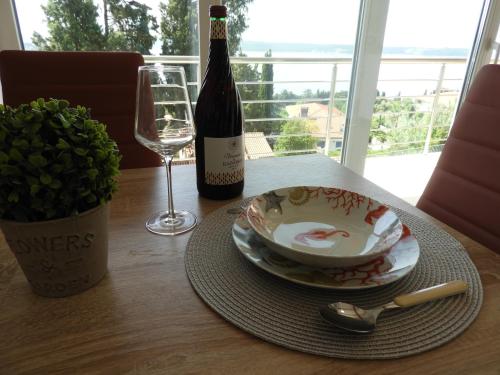 a table with a bottle of wine and a bowl and spoon at Red Rose Apartment in Portorož