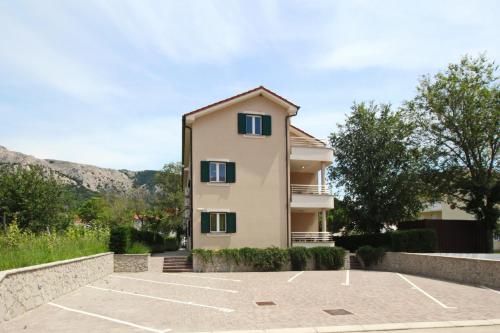 a building with a parking lot in front of it at Apartments Smojver Stipe in Baška