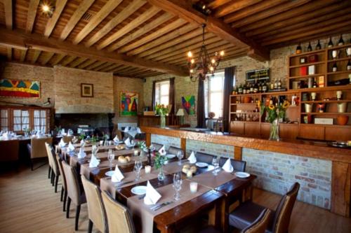 un comedor con una mesa larga y un bar en Hostellerie Hof Ter Doest en Lissewege