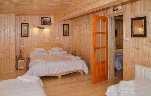 two beds in a room with wooden walls at Malom Apartman in Derekegyház