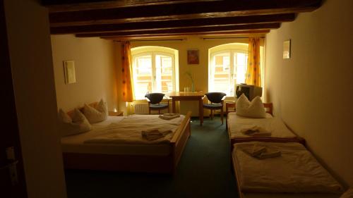 a room with two beds and a table and chairs at Altstadt Pension Hafenblick in Stralsund