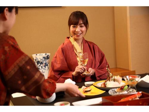a woman sitting at a table with a glass of wine at Kashoutei Hanaya in Noboribetsu