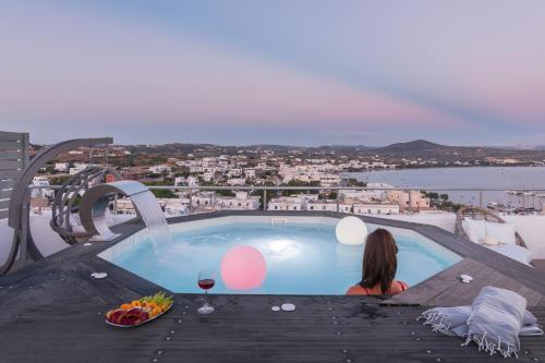 a woman sitting on a table next to a swimming pool at Uncle's House luxury Suites in Adamas