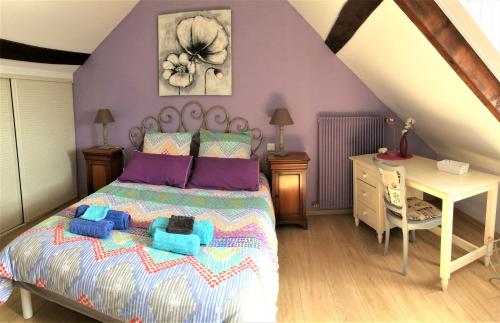 a bedroom with a bed with purple walls and a desk at Gite de Sologne "les galoches" in Dhuizon