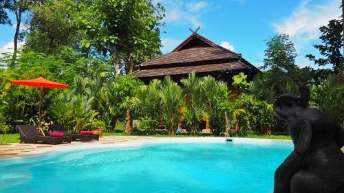 a statue in front of a swimming pool with a building at Nan Seasons Boutique Resort in Nan