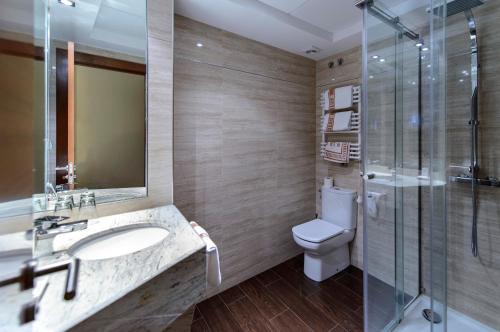 uma casa de banho com um lavatório, um WC e uma cabina de duche em vidro. em Hotel Restaurante La Peseta em Astorga