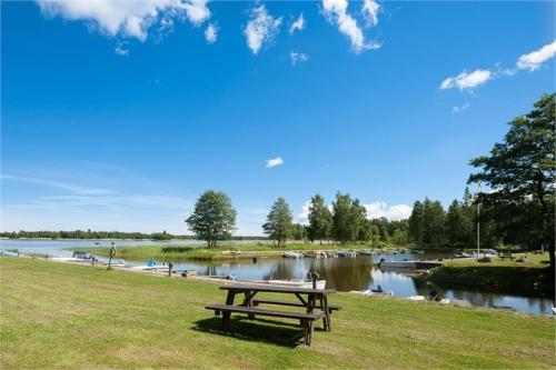 a picnic table sitting in the grass next to a lake at Karlholm Snatra Stugområde in Karlholmsbruk