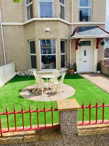 two chairs and a table in the yard of a house at The Snug Garden Apartment in Llandudno