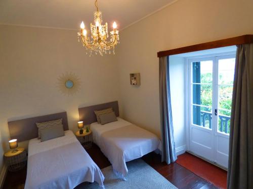 a bedroom with two beds and a chandelier at Quinta Do Solar - Exclusivo Perfeito para Famílias in Ponta Delgada