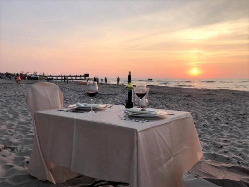 a table with two glasses of wine on the beach at Ledan in Chłopy