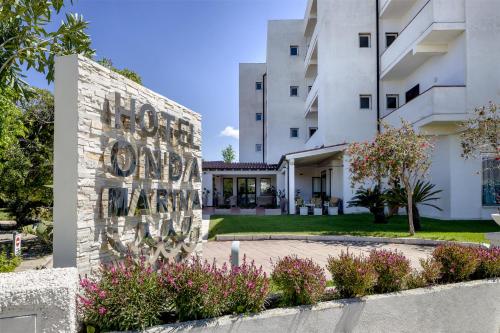 a sign in front of a building with flowers at Hotel Onda Marina in San Teodoro
