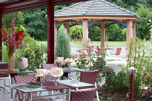 a gazebo with tables and chairs in a garden at Le Rhien Hôtel-Restaurant in Ronchamp