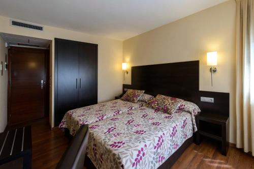 1 dormitorio con 1 cama grande con colcha de flores en Hotel Restaurante La Peseta en Astorga