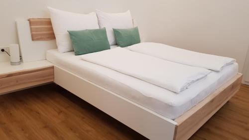a large white bed with two green pillows on it at Seesuiten Mörbisch in Mörbisch am See