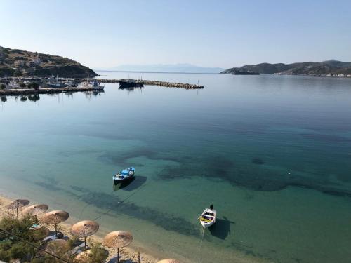 two boats in the water with umbrellas on a beach at Thalassa view in Áyioi Apóstoloi