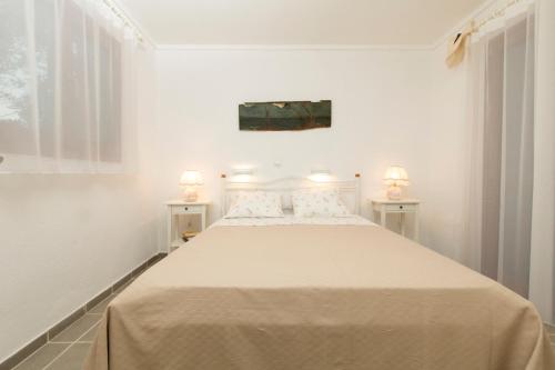 a white bedroom with a large bed with two lamps at Functional house by the sea at Ierissos in Ierissos