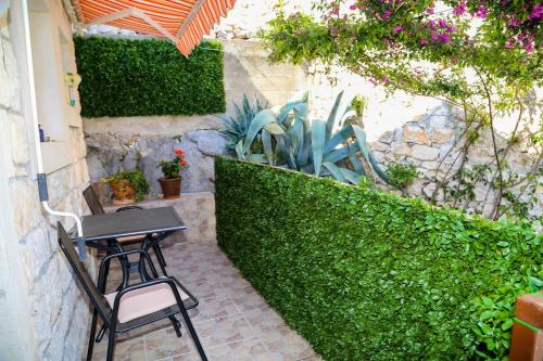 a table and chairs sitting on a patio next to a hedge at Apartments Seka in Hvar