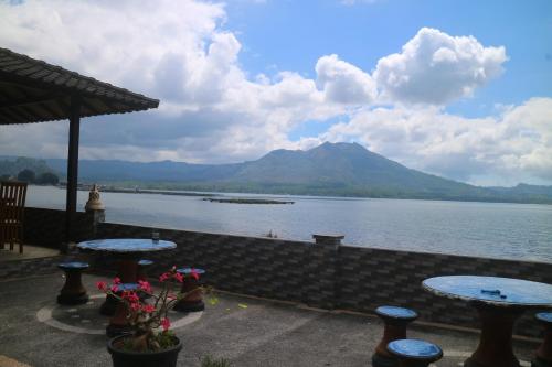a view of a lake with tables and a mountain at Batur Green Lakeview in Kintamani Bali in Kintamani