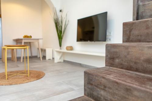 a living room with a television and a stool at Thea Suites Naxos in Agios Prokopios