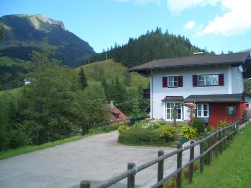 ein rotes und weißes Haus mit einem Zaun an einer Straße in der Unterkunft Haus Ortner in Russbach am Pass Gschütt