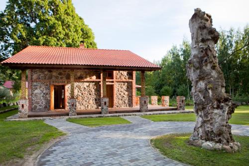 a stone building with a red roof in a park at Linnumaja Guesthouse in Uulu