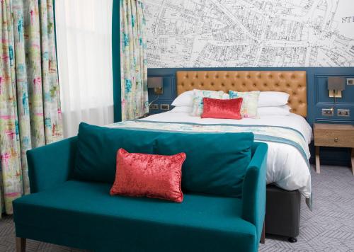 a bedroom with a bed and a couch with red pillows at The Angel Hotel in Leamington Spa