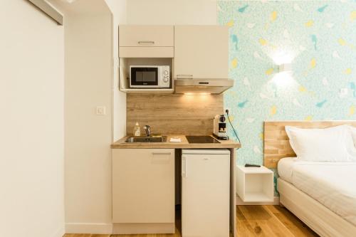 une petite cuisine avec un évier à côté d'un lit dans l'établissement Nice Home - Studios Lido, à Nice