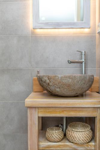 a bathroom with a stone sink on a wooden table at Thea Suites Naxos in Agios Prokopios
