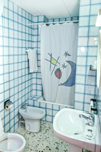 a blue tiled bathroom with a sink and a shower curtain at Raco d'en Pepe in Calella