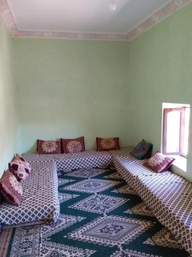 a room with two beds and a rug at Maison D'hote Amazir in Boumalne