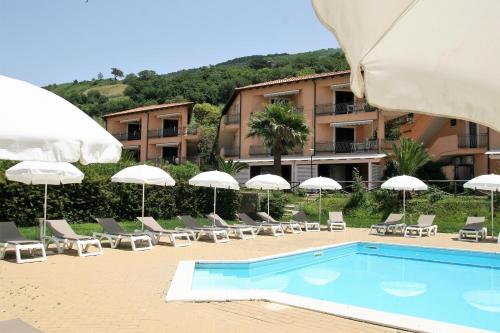 un complejo con piscina, sillas y sombrillas en Residence Pietre Bianche ApartHotel, en Pizzo