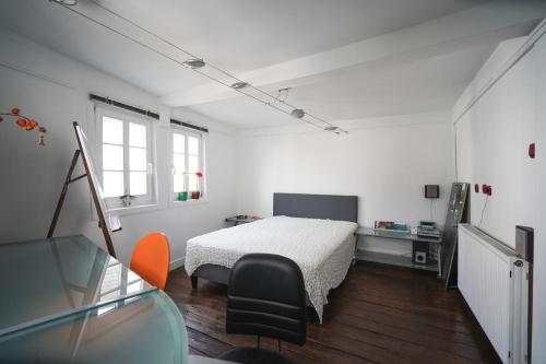 a white bedroom with a bed and a chair at Hexenhäuschen Dreieichenhain in Dreieich