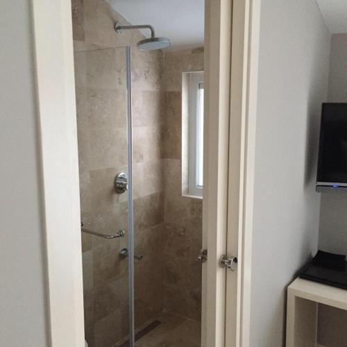 a bathroom with a shower with a glass door at Teos Lodge Pansiyon in Siğacık