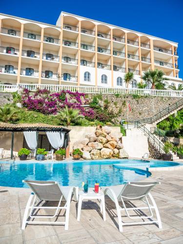 a resort with a swimming pool and two chairs and a table at Paleo ArtNouveau Hotel - Adults Only in Paleokastritsa