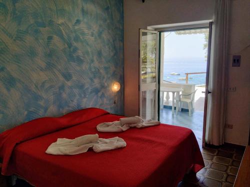 a bedroom with a red bed with towels on it at La Dea del Mare in Ischia