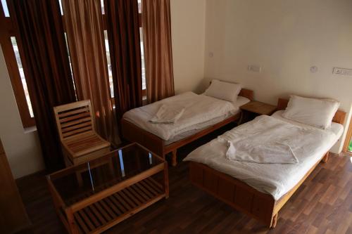two twin beds in a room with wooden floors at Smanla guest house in Leh