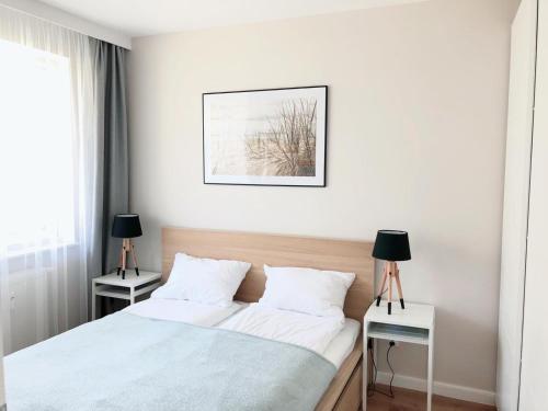 a white bedroom with a bed and two night stands at Blue Park Apartament Bliżej Morza Kasprowicza in Kołobrzeg