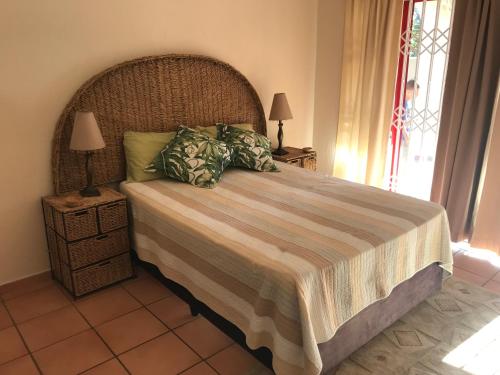 1 dormitorio con 1 cama grande y cabecero de madera en Jd’s number 6 en Uvongo Beach