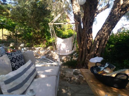 a white couch sitting in front of a tree at Greekowl apartments in Skiathos Town