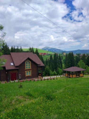 a wooden house in a field with a green field at GUTSULWOOD in Yablunytsya