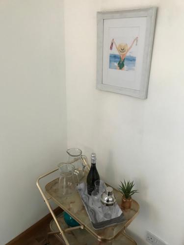 Hebridean Holiday House في ستورنووي: طاولة زجاجية مع نظارة وصورة على الحائط
